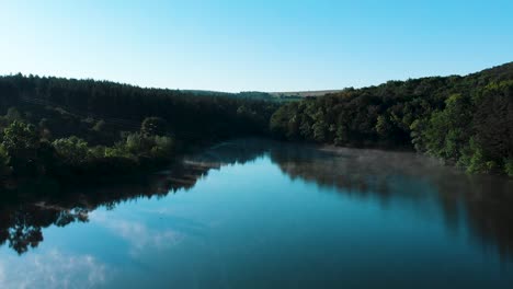 Early-morning-aerial-shot-over-glossy-lake-with-birds