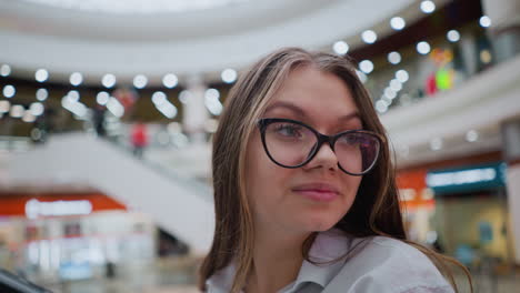 close up of lady on escalator with glasses looking around attentively in a busy modern mall, capturing her observant expression and vibrant retail setting