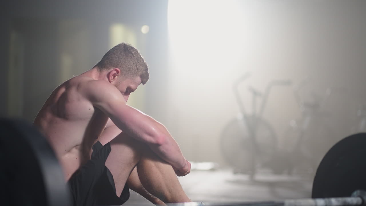 체육관에서 집중적인 운동을 한 후 휴식을 취하는 지친 젊은 남성. 체육관에서 근력 훈련 운동을 한 후 피곤한 건강한 남성. 강렬한 운동을 한 후 서서 휴식을 취하는 피곤한 남성 피트 모델.