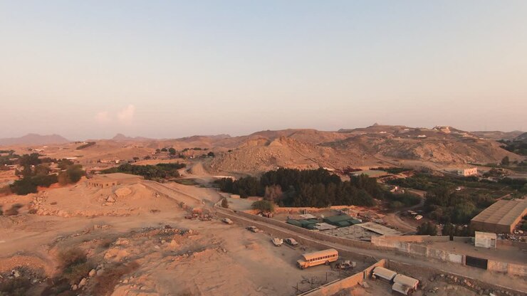 Volo FPV sopra un'area verde e sabbiosa verso colline lontane, Arabia Saudita.
