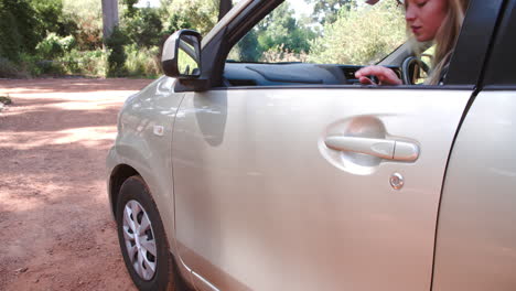 young woman getting out of a car in a rural car park