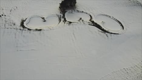 rising aerial shot of snow covered bunker and fairway on a golf course