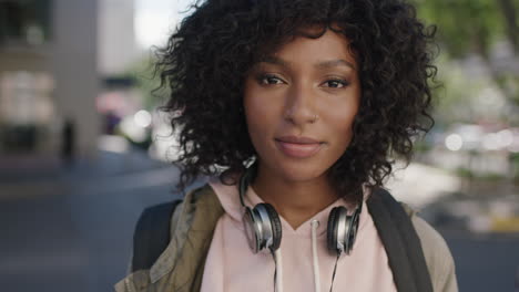 retrato de una joven atractiva mujer afroamericana mirando pensativa en la calle de la ciudad con auriculares