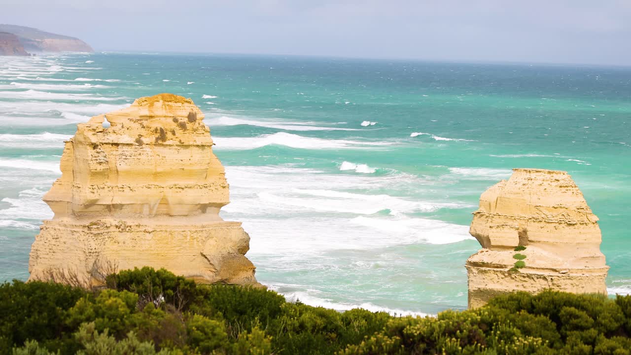 Stunning coastal rock formations with vibrant ocean waves and lush greenery under bright daylight at Port Campbell, Australia