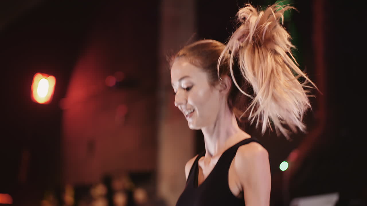 cámara lenta de una mujer atlética sonriente haciendo ejercicio usando una cuerda para saltar en el estudio de fitness