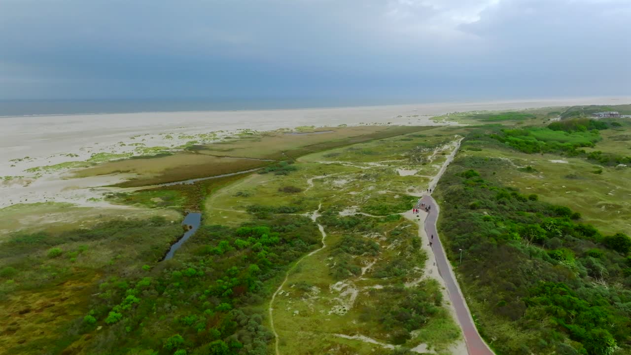 The northernmost point of Germany. Aerial pan left overlooking Borkum island coastline with lush green vegetation and wide sand beach