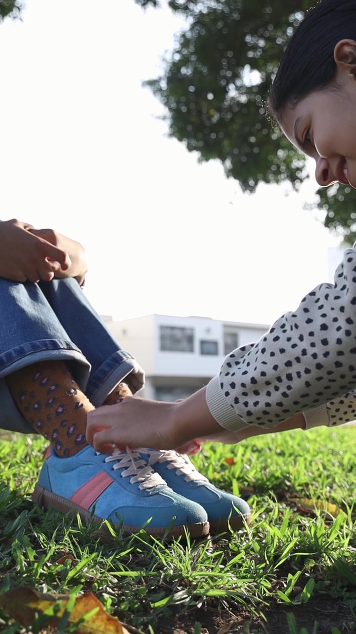 Primo piano di mani che allacciano i lacci su sneakers blu nell'erba