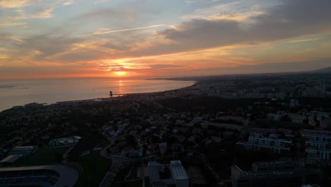 Vista-Aérea-De-Un-Tranquilo-Amanecer-Sobre-La-Ciudad,-Con-El-Sol-Proyectando-Su-Cálido-Resplandor-Sobre-La-Superficie-Del-Agua,-Creando-Una-Escena-Serena-Y-Pintoresca