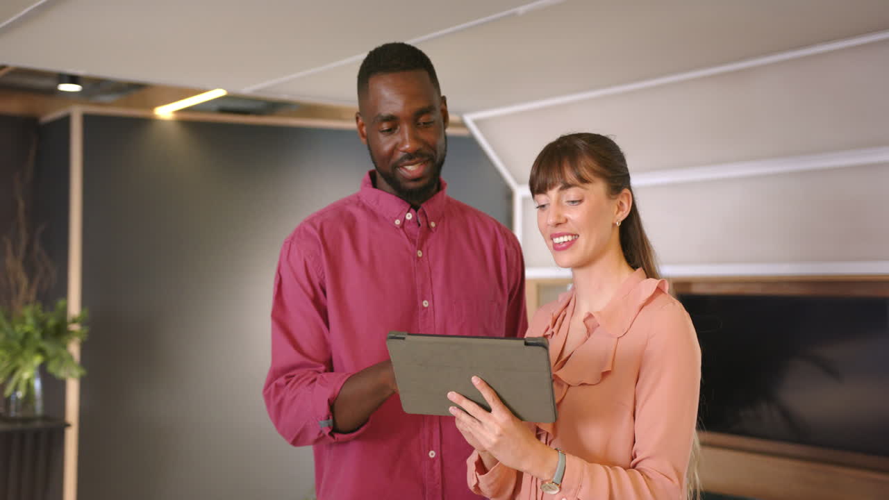 Business diverse colleagues discussing project, using tablet and smiling in office