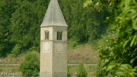 Mittlere-Aufnahme,-Malerischer-Blick-Auf-Den-Kirchturm-Von-Altgraun-An-Einem-Strahlend-Sonnigen-Tag-In-Italien,-Im-Hintergrund-Fahren-Auto-Und-Motorrad-An-Der-Autobahn-Vorbei