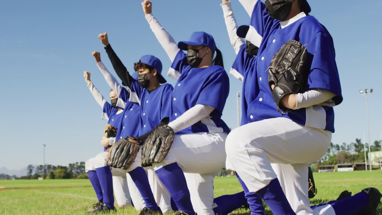 얼굴 마스크를 입은 여성 야구 선수들의 다양한 팀이 팔을 들고 무 ⁇ 을  ⁇ 고 있습니다.