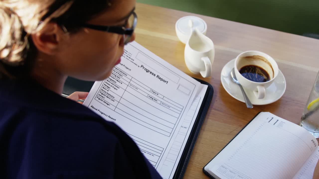 mujer de negocios haciendo papeleo en un café.