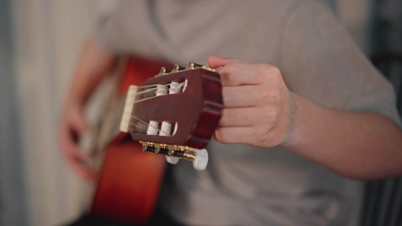 Mano in primo piano che accorda la paletta della chitarra, lo studente regola le meccaniche e controlla l'intonazione, attenta configurazione e preparazione prima della lezione, movimento preciso sotto la supervisione dell'insegnante in un ambiente di scuola di musica