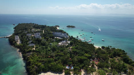 Aerial-view-circling-a-touristic-island-in-the-Caribbean-with-buildings-and-trees,-Dominican-Republic