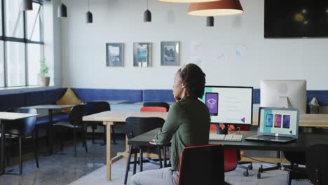 mujer de negocios afroamericana sentada a la mesa y usando un teléfono inteligente sola en la oficina
