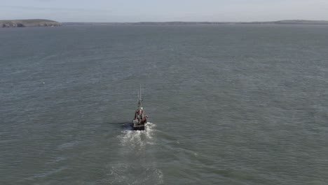antena: pequeño barco pesquero se dirige al mar frente a los acantilados costeros irlandeses