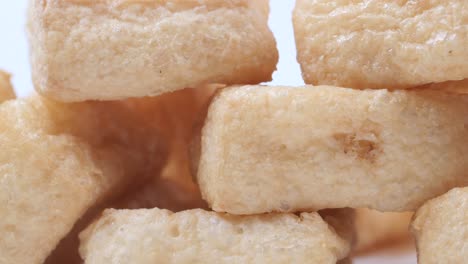 una pila de tofu frito en un plato sobre un fondo blanco .