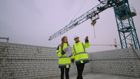 Dos-Ingenieros-Civiles-Están-Discutiendo-El-Proceso-De-Construcción-En-El-Capataz-Del-Sitio-De-Construcción-Y-La-Arquitecta