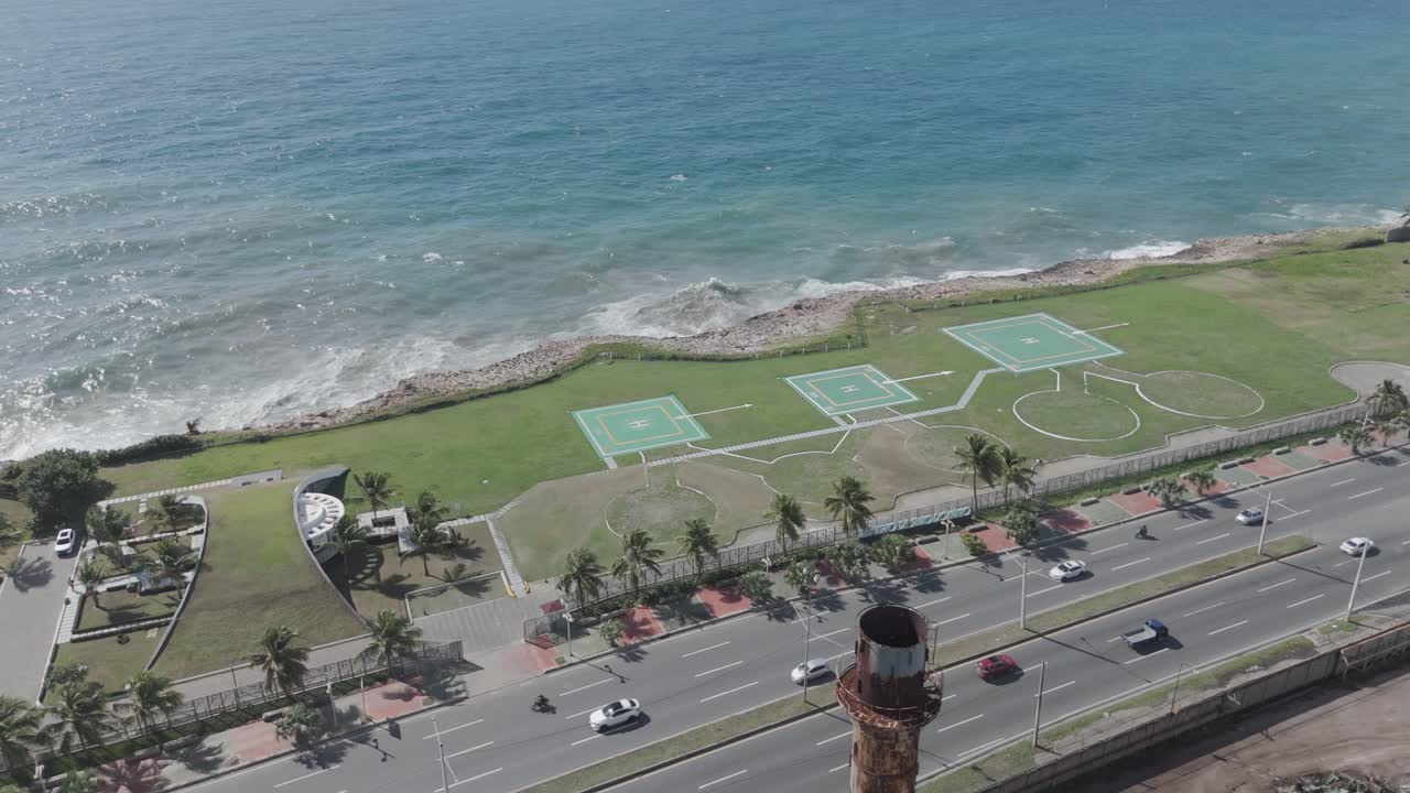 Helipad at Caribbean sea coastline in Santo Domingo. Sunny day with palm trees along avenue. Traffic scene. Aerial top down shot.