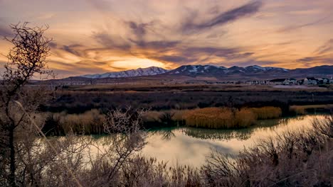 day-to-night mountain sunset time lapse with the sky reflecting off the surface of the river - zoom out to reveal a wide angle panorama view