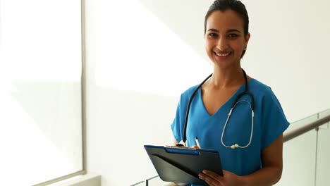 Portrait-of-female-doctor-writing-on-clipboard-in-the-passageway