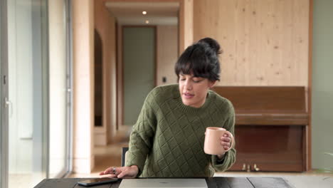 woman in cozy sweater closing laptop at home with coffee mug nearby