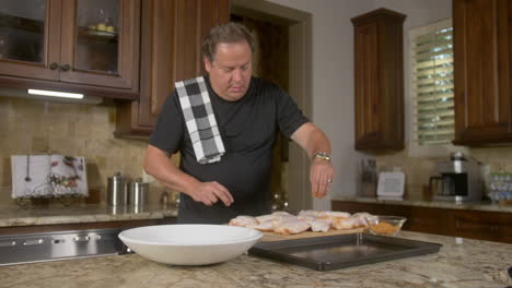 man sprinkles spice mix on to chicken for grilling or bbq