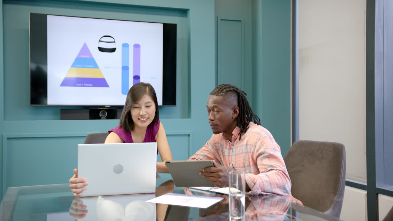 Business colleagues discussing project, using laptop and tablet in office meeting