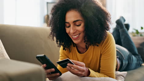woman using credit card and smartphone on couch