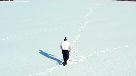 man running in the snow towards fishing hole