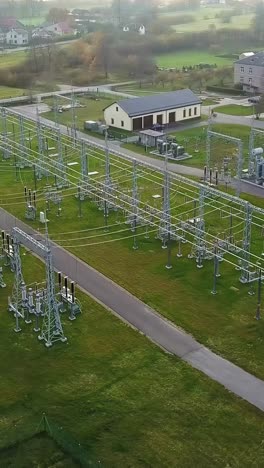 drone circles above electrical substations that transform and distribute electricity safely - next to a village.