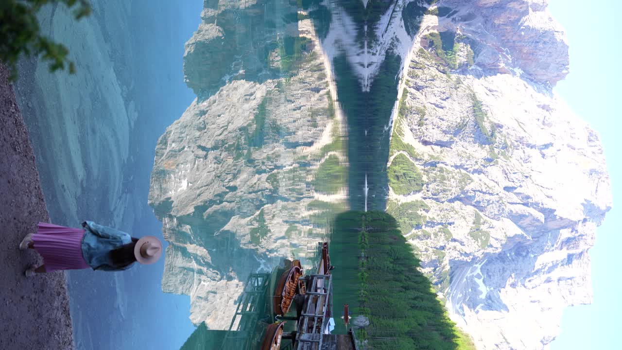 mujer sola disfrutando del impresionante paisaje de las dolomitas junto a un lago espejo con el reflejo de la montaña croda del becco, italia