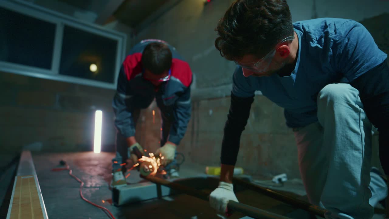 Construction Workers Cutting Metal Pipes with Angle Grinder