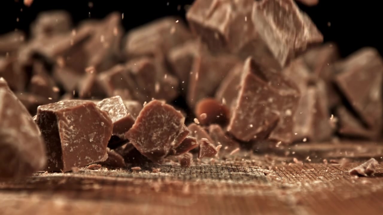 Pezzi di cioccolato che cadono al rallentatore su una superficie di legno