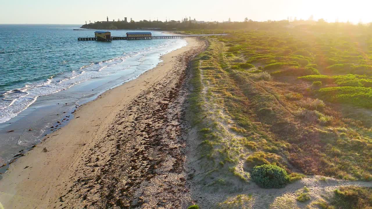 Aerial view of a serene coastal path in Bellarine, Victoria, with golden sunlight and gentle waves