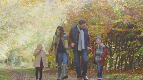 Familie-Mit-Reifen-Eltern-Und-Zwei-Kindern,-Die-Händchen-Haltend-Entlang-Der-Strecke-In-Der-Herbstlichen-Landschaft-Laufen