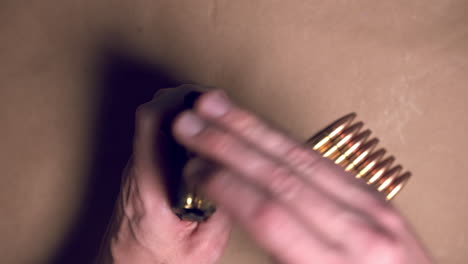 close up shot of hands loading ar-15 magazine with bullets