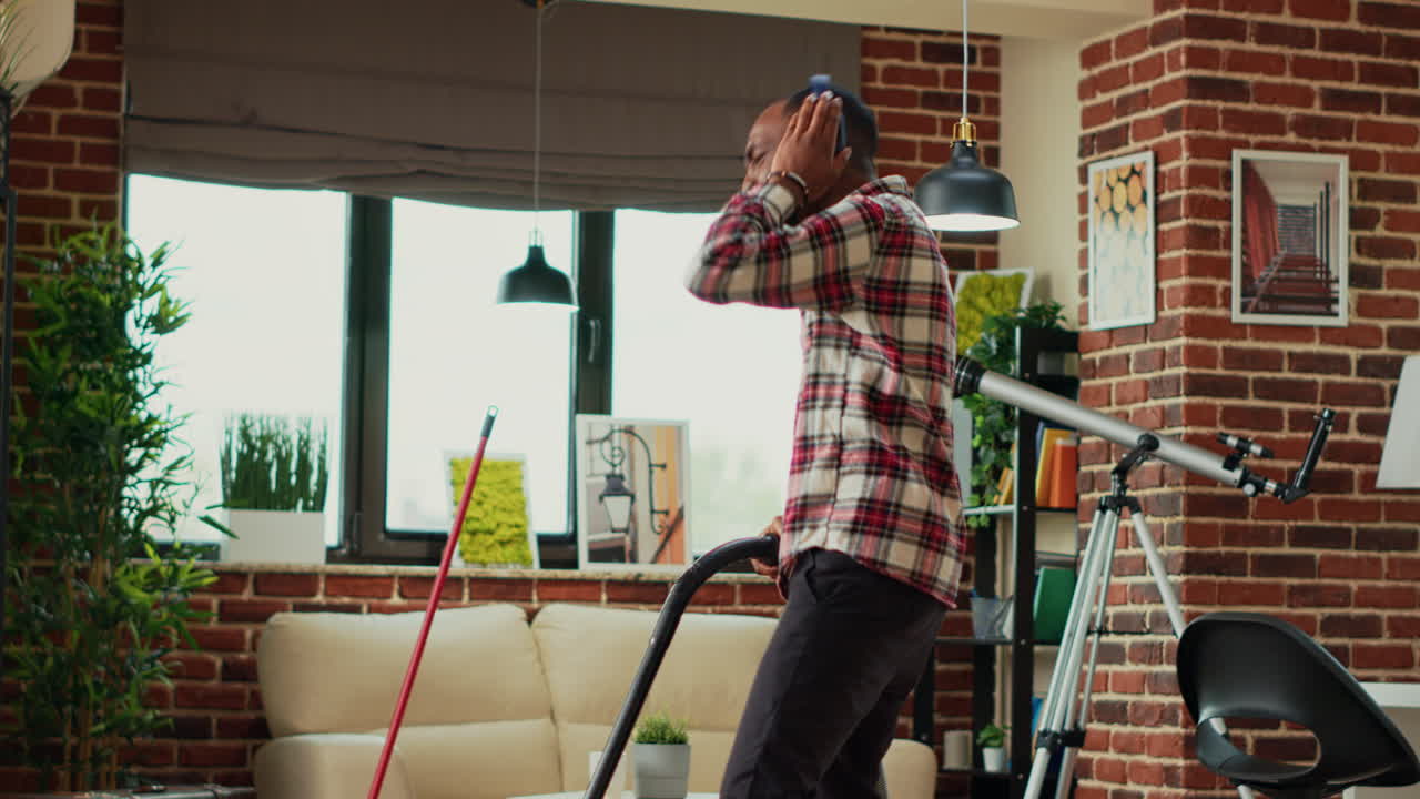 Modern cheerful adult using vacuum cleaner to clean apartment floors