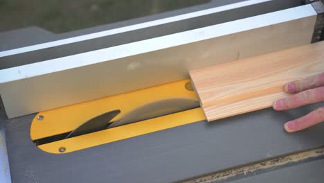 carpenter joiner cutting slats of 2 x 4 wood timber on circular saw whilst on job site building a house