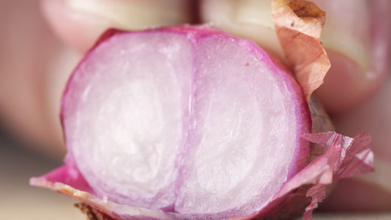 Primo piano di una cipolla rossa che viene affettata con un coltello affilato su un tagliere durante la preparazione del pasto, ideale per video di cucina, contenuti di ricette e la preparazione dei cibi in cucina.