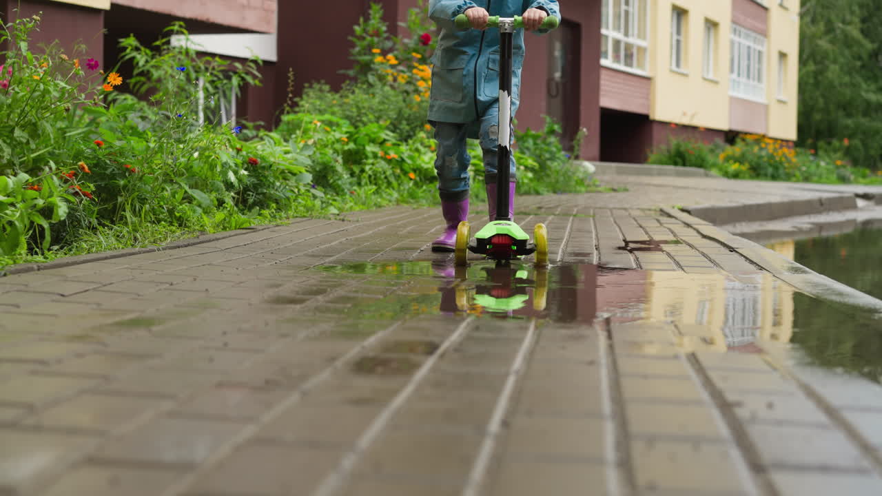 Child glides on scooter in rainy weather adventurous kid propels forward on kick scooter relishing