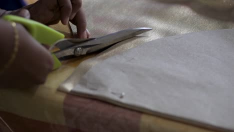 cortando lenta y rotundamente la tela con una tijera de aluminio y color verde sobre la mesa por parte de una mujer del sur de asia ángulo de cámara estático clip de rollo b