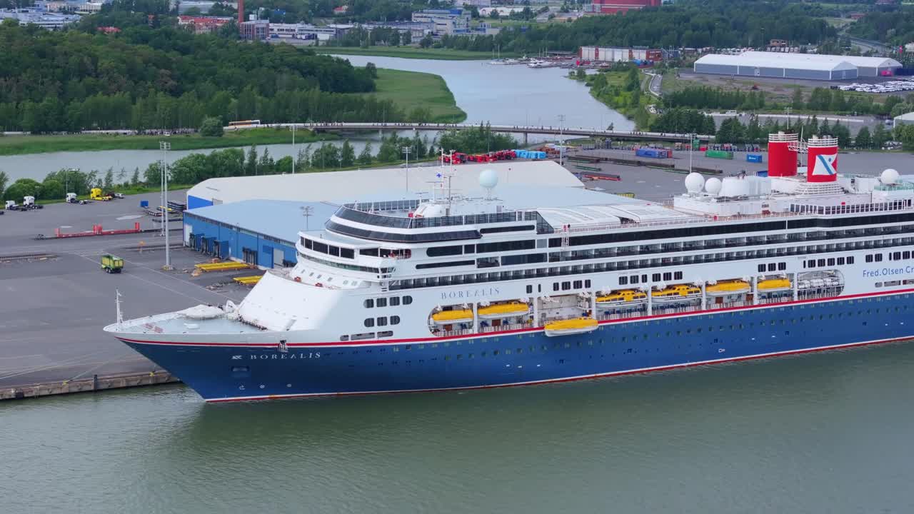 Fred.Olsen Cruise Lines passenger ship BOREALIS alongside in port. Lifeboat lowered for training. Moving aerial side view.
