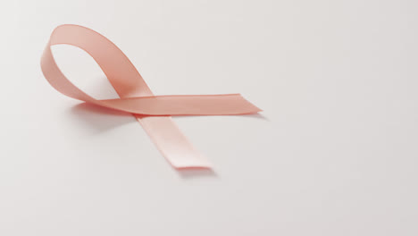 video of peach pink uterine cancer ribbon on white background