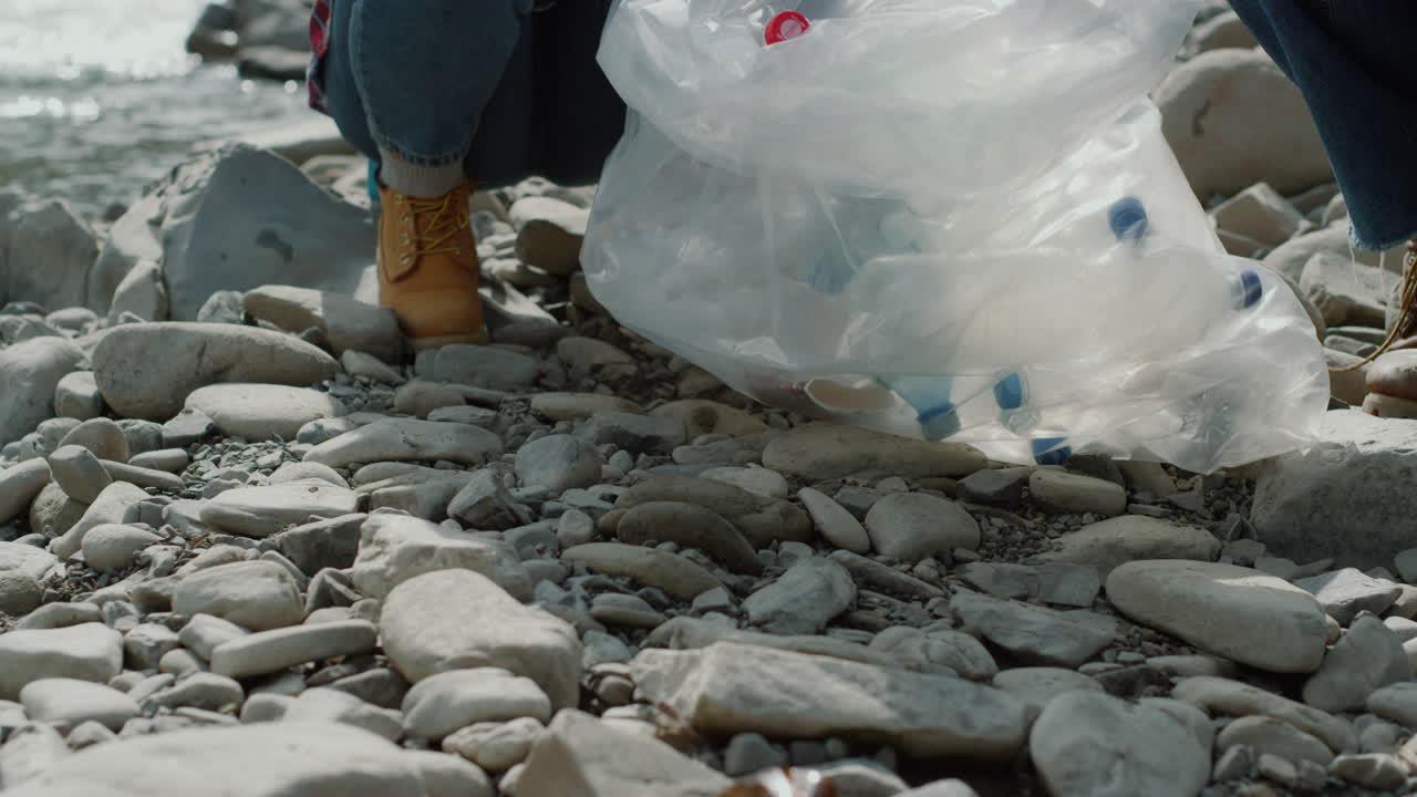 voluntarios recogiendo botellas en bolsas. mujer y hombre limpiando el río de basura
