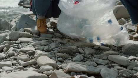 Volunteers-collecting-bottles-into-bag.Woman-and-man-cleaning-river-from-garbage