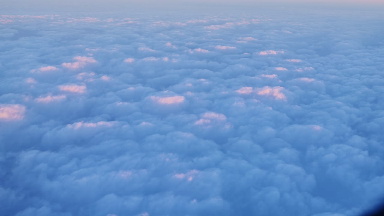 Serene sunrise seen from airplane above textured clouds glowing in warm light