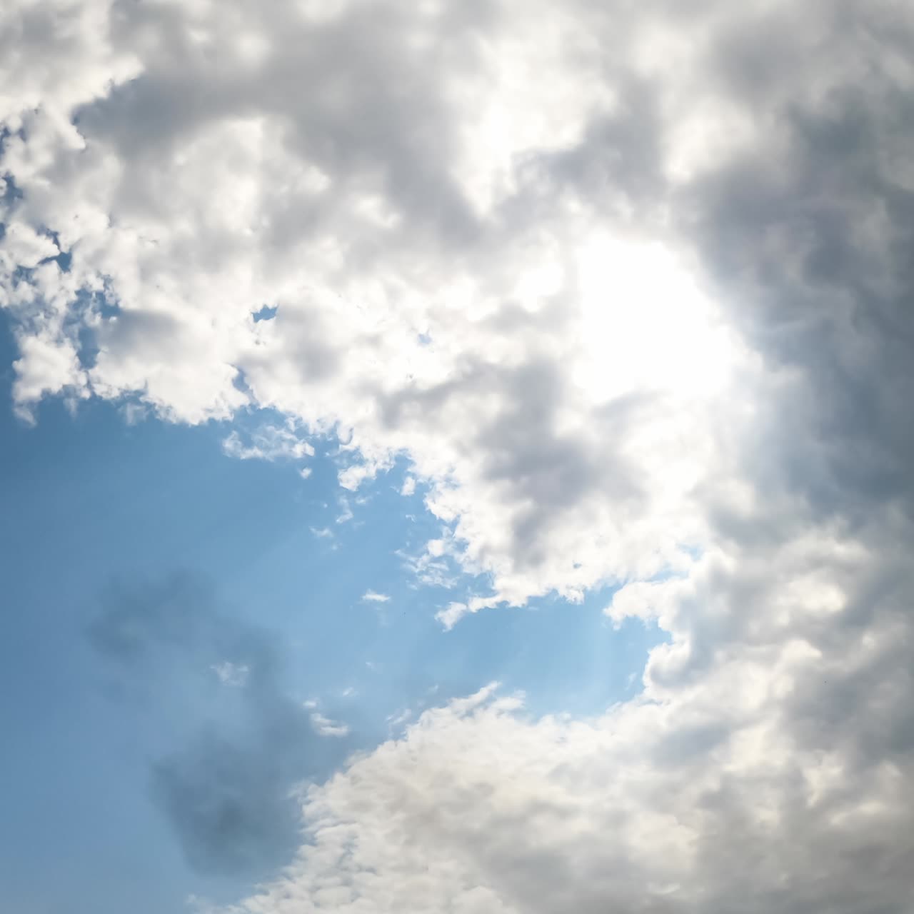 Large rainy clouds covering the sky. Blue sky rarely appears from behind the dramatic cloudscape. Low angle view. Timelapse