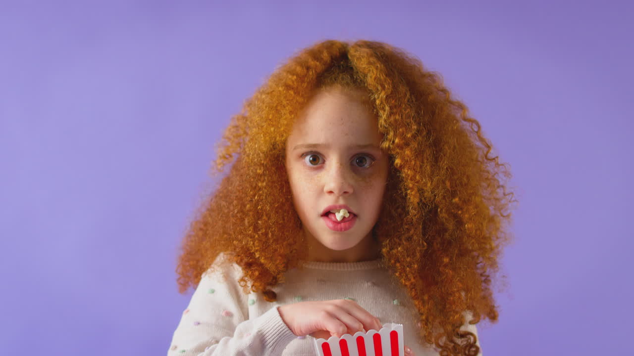 Scared Girl Watching Horror Movie And Spilling Popcorn At Cinema Against Purple Background