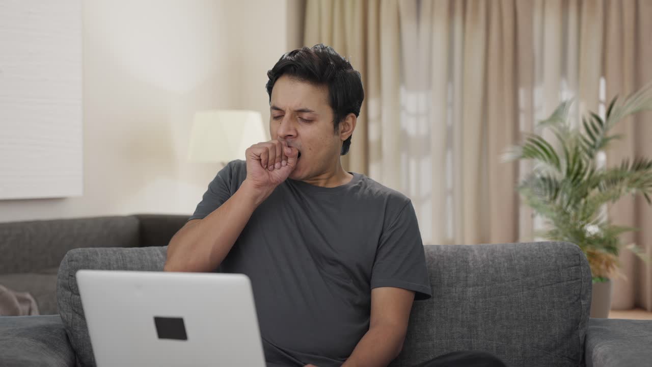 Tired and lazy Indian man working on laptop